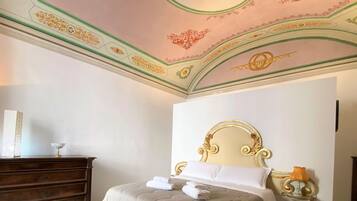 Una camera d'hotel con un letto, una cassettiera e un soffitto decorato.