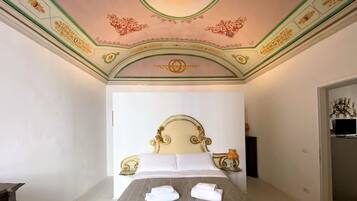 Ein Hotelzimmer mit einem großen Bett, einer verzierten Decke und einem kleinen Tisch mit einer Lampe.