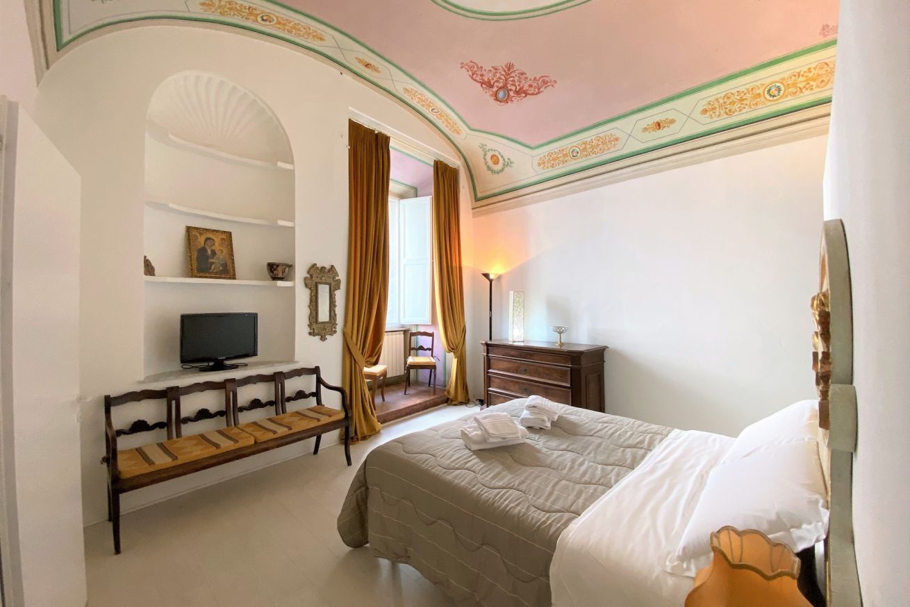 A hotel room with a bed, a television, a bench, a dresser, and a chair.