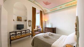 A hotel room with a bed, a television, a bench, a dresser, and a chair.