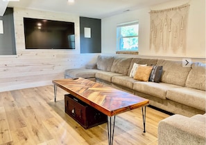 Relax in this stylish living room with a large flat-screen TV, comfortable sofa, and wooden floor.