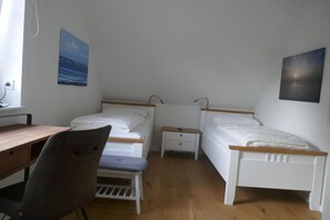 Une chambre avec deux lits simples, un bureau et une chaise.