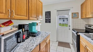 A kitchen with wooden cabinets, a coffee maker, a microwave, and a coffee machine. There is a chalkboard with a motivational quote on the wall.