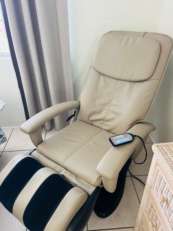 A reclining chair with a massage function, a remote control, and a power outlet.