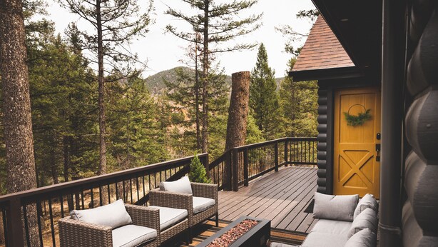 A wooden deck with wicker furniture and a fire feature.