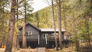 A cabin with a wooden exterior, a balcony, and a staircase leading to the entrance.