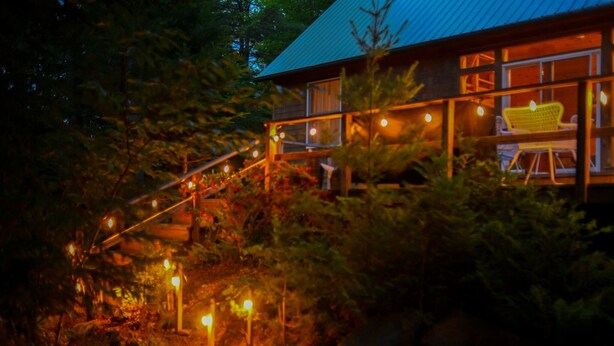 Eine Holzhütte mit überdachter Veranda und Lichterkette.