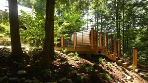 Eine Holzbrücke in bewaldeter Landschaft mit Metallgeländer und Steinstufen.