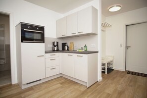 A compact kitchen with white cabinets, a built-in oven, a coffee maker, and a small countertop.