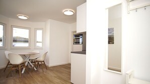 A modern kitchen with a built-in oven and a dining area with a table and chairs. - Die Ferienwohnung Dünenrose im Haus Südperd - Haus Südperd (Mönchgut)