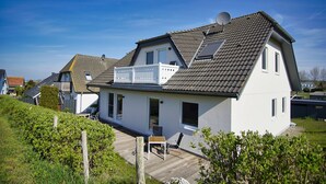 A two-story house with a sloped roof, a balcony, and a satellite dish. - Die Ferienwohnung Dünenrose im Haus Südperd - Haus Südperd (Mönchgut)