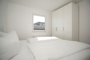 Ein Schlafzimmer mit Bett, Fenster und Kleiderschrank.
