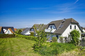 A row of modern houses with sloped roofs, white walls, and satellite dishes.