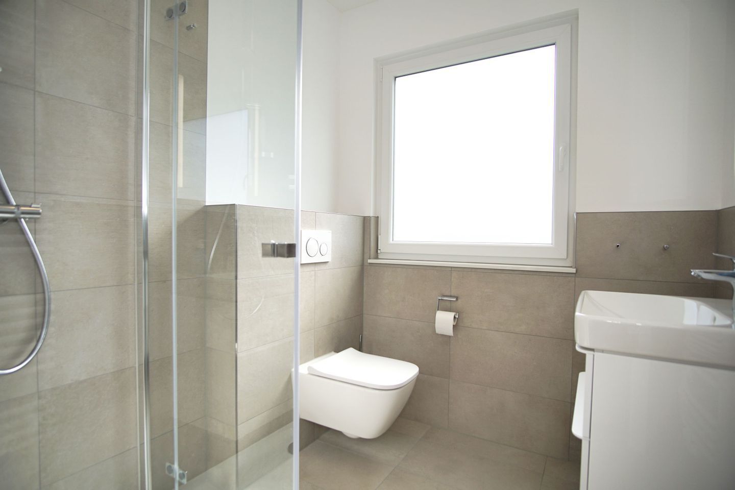 A modern bathroom with a glass shower enclosure, a toilet, and a sink.