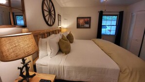 Une chambre à coucher avec un grand lit, une tête de lit en bois, une lampe de chevet, une fenêtre avec des rideaux et un ventilateur de plafond.