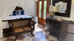 Un dormitorio con una cama a dosel, un aparador de madera, un espejo y un suelo a cuadros.