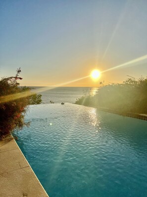 A clear view of a swimming pool with a sunset in the background.