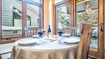 Mesa lista para dos personas, con una botella de vino, copas y pan.