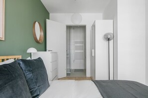 Un dormitorio moderno con cama, mesita de noche, lámpara y armario.
