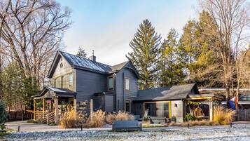 A two-story house with a dark gray exterior, a sloped roof, and a front porch with a swing chair.