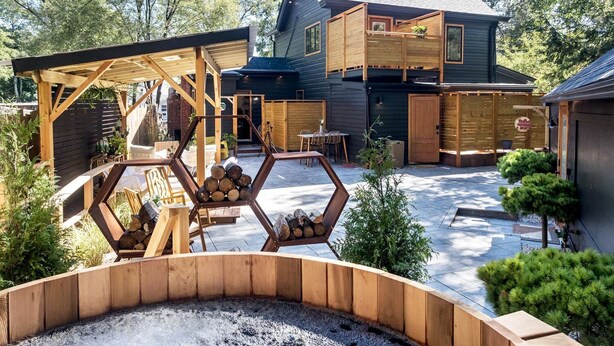 A modern house with a wooden deck, a fire pit, and a covered outdoor seating area. - The Herwood Inn (Woodstock)