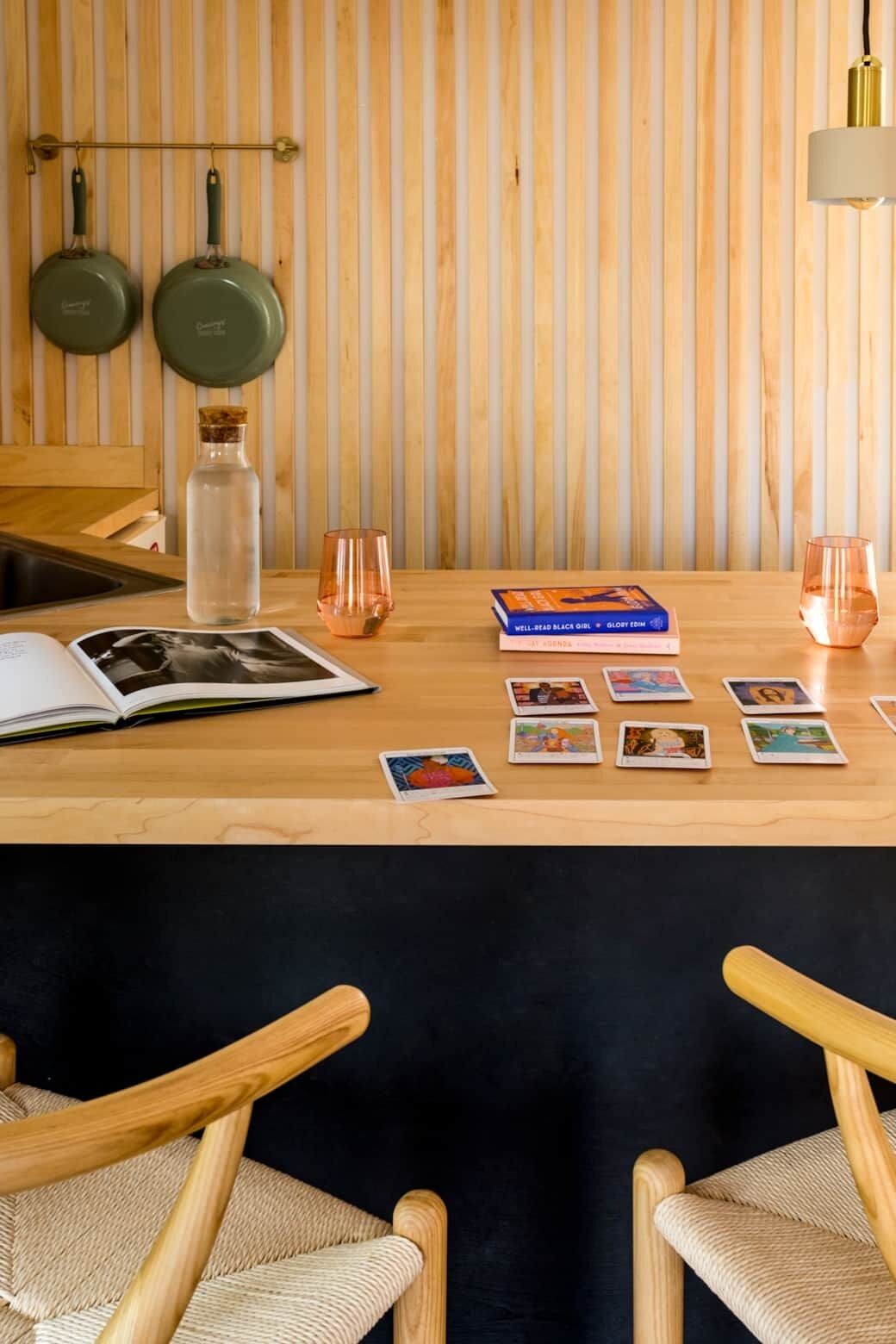 Une table en bois avec un livre, une bouteille en verre et un jeu de cartes.