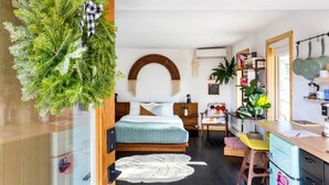 A modern bedroom with a bed, a small desk, and a kitchenette area. - The Herwood Inn (Woodstock)