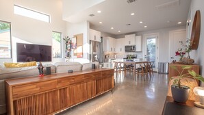 A modern kitchen with white cabinets, a wooden island, and a dining area with chairs.