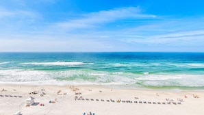 A beach with clear skies, calm waves, and people sunbathing.