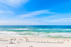 A beach with clear skies, calm waves, and people sunbathing.