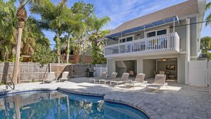 A two-story house with a swimming pool, outdoor seating, and a balcony.