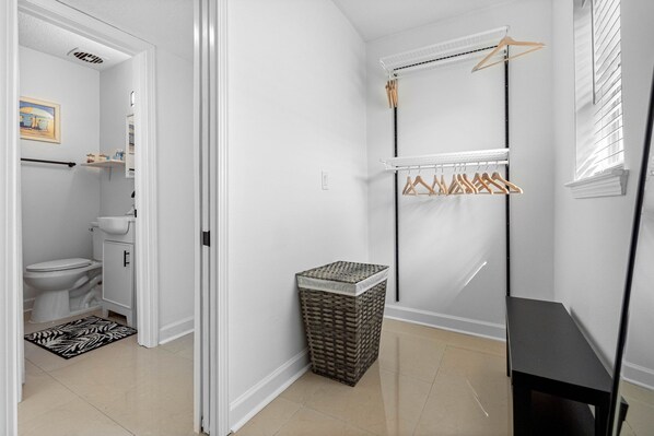 A clean, modern bathroom with a toilet, sink, and a small laundry area with a drying rack.