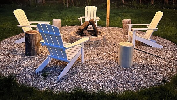 Ein Sitzbereich mit Adirondack-Stühlen, einem Feuerkorb und Lichterketten.