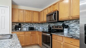 A kitchen with wooden cabinets, a stainless steel refrigerator, a microwave, and a stove. - Cape Coral Serenity Waterfront Walking Distance to Shopping & Restaurants (Cape Coral)