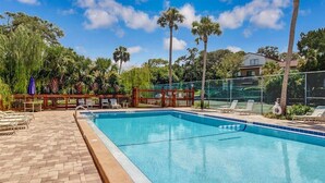 A rectangular swimming pool with a wooden deck and lounge chairs. - Mermaid Den - Hosted By Moore AI Rentals (Fernandina Beach)