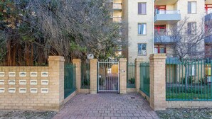Una entrada portonada a un edificio residencial, con un camino de ladrillo que conduce a la puerta.