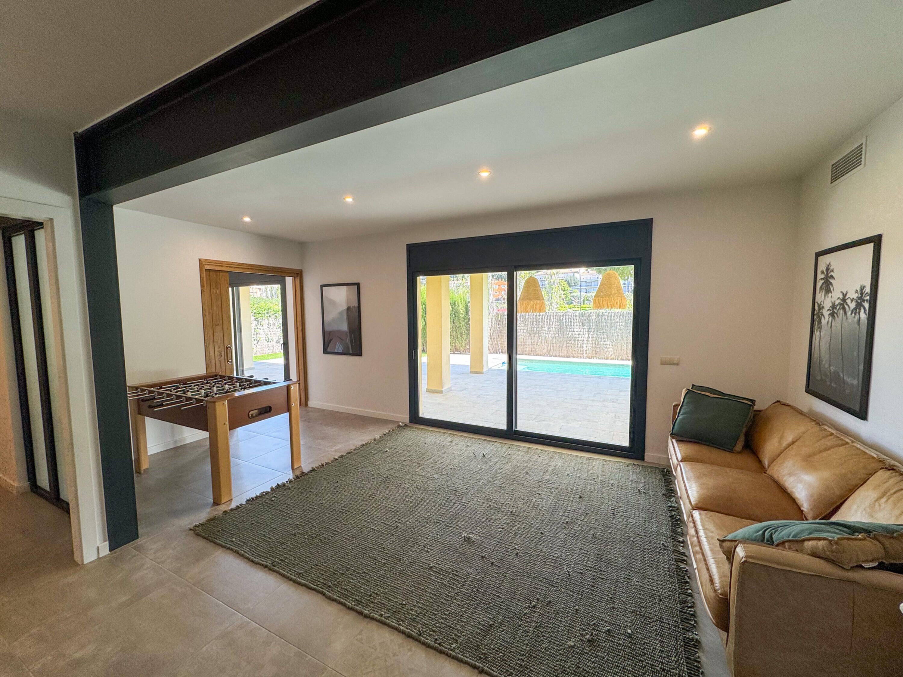 A spacious living area with a foosball table, a large rug, and a leather sofa.