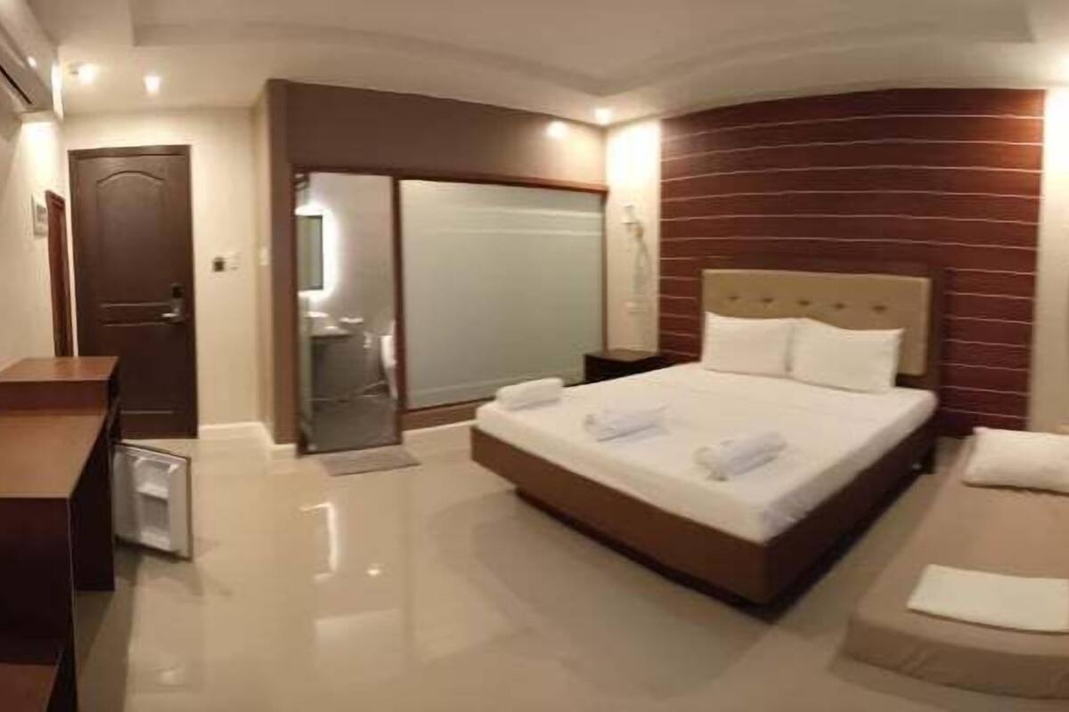 A hotel room with a large bed, a desk, a mirror, and a sliding door.