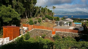 A coastal property with a stone wall, wooden fence, and a small building with a door and window. - Adegada Quinta- Beautiful Cottage in Madalena (Madalena - Pico)
