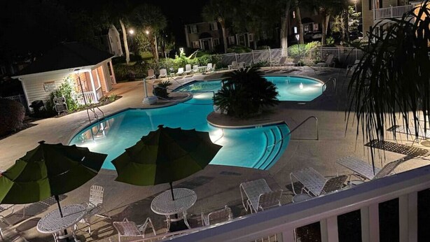A swimming pool with lounge chairs and umbrellas, surrounded by trees and buildings. - C2 Pet-friendly, 1 BR, 1 BA, sleeps 5 (St. Simons Island)