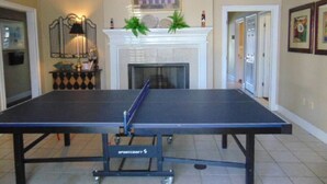 A ping pong table in a room with a fireplace, framed artwork, and a door leading to another room. - C2 Pet-friendly, 1 BR, 1 BA, sleeps 5 (St. Simons Island)