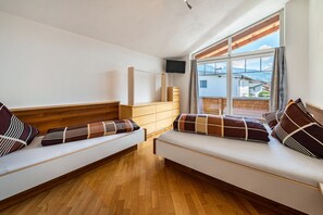 Quarto com duas bancadas de madeira, uma TV de tela plana na parede e uma grande janela com vista para edifícios.