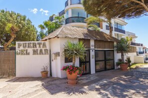 Un edificio con un letrero que dice 'PUERTA DEL MAR', una estructura de techo de paja y una entrada con portones.