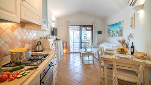 A modern kitchen with a dining area, a view to the outside, and a dining table set with plates and a fruit bowl. - Dimora di Rosy Pittulongu, Pittulongu, Italy (Pittulongu)