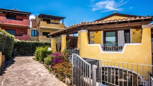 A yellow building with a tiled roof, a stone pathway, and a metal gate. - Dimora di Rosy Pittulongu, Pittulongu, Italy (Pittulongu)