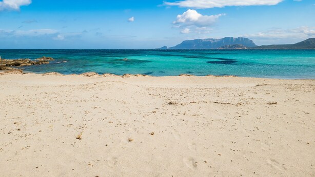 A beach with clear turquoise water, sandy shore, and distant mountains. - Dimora di Rosy Pittulongu, Pittulongu, Italy (Pittulongu)