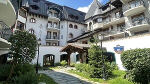 A courtyard with a stone pathway, surrounded by lush greenery and a building with multiple balconies and arched windows. - Le Cristal GM7 Mountain View, Pool, Private Sauna & Parking, Argentière (Chamonix), France (Argentière (Chamonix))