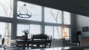 A dining area with a table and chairs, large windows with a view of trees, and a chandelier. - The Little Red Barn w/ Spectacular Views & Less than 1 mile - Blue Ridge Parkway (Hillsville)