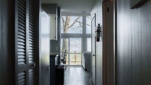 A narrow hallway with a view to a balcony, a refrigerator, and a door with a light fixture. - The Little Red Barn w/ Spectacular Views & Less than 1 mile - Blue Ridge Parkway (Hillsville)