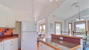 Una cocina con armarios blancos, un refrigerador blanco, encimera de granito y una zona de comedor con banco.